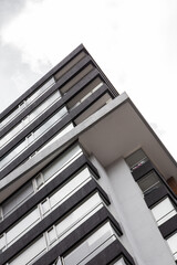 Wall Mural - A tall black building viewed from below, emphasizing its height and sleek, modern design. The dark exterior contrasts with the sky, creating a striking and dramatic architectural effect.