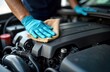 © Pete - Man in blue gloves cleans car engine compartment with cloth. Person cares for car. Maintenance job in garage. Auto repair process. Focus on cleanliness, detail. Car mechanic works carefully. Engine