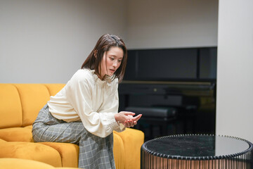 Wall Mural - A Japanese woman in her 30s is relaxing on the sofa in her living room.