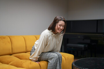 Wall Mural - A Japanese woman in her 30s is relaxing on the sofa in her living room.