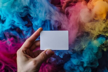 Poster - Hand holding blank white card against vibrant colorful smoke background.