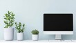 © WACHI - A minimalist workspace featuring a computer and three potted plants against a light blue wall.