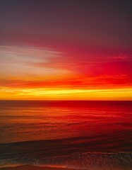 Wall Mural - Fiery sunset over the ocean.  Warm colors paint the sky and sea.