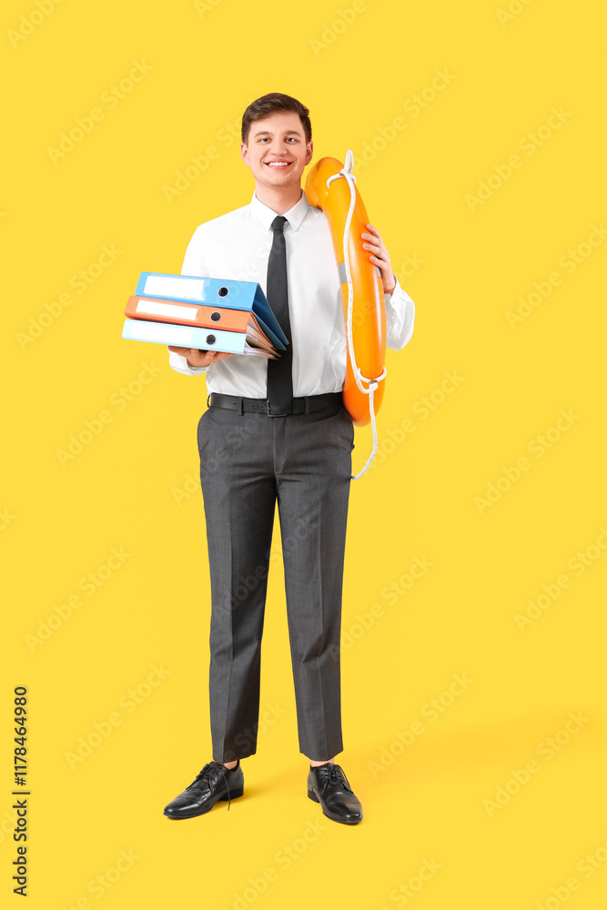 Young businessman with lifebuoy and documents on yellow background