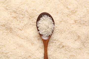 Wooden spoon with raw rice as background