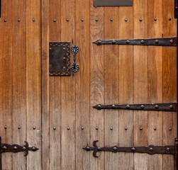 Close up of old wooden doors with heavy metal hinges in stone building