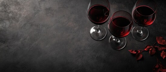 Poster - Elegant red wine glasses on a rustic table with dark background creating space for promotional text or advertisements related to wine.