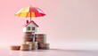 © Tahubulat - A house model shielded by an umbrella on a pile of coins, highlighting the significance of insurance in attaining financial stability