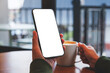 © Farknot Architect - Mockup image of a woman holding mobile phone with blank desktop screen while drinking coffee in cafe