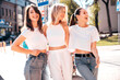 © halayalex - Three young beautiful smiling hipster female in trendy summer white t-shirt  and jeans clothes. Sexy carefree women posing in street. Positive models having fun, going crazy. In sunny day