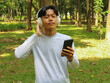 © Lailar Studio - Asian man relax in nature using mobile phone while listening music