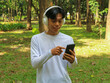© Lailar Studio - Asian man relax in nature using mobile phone while listening music