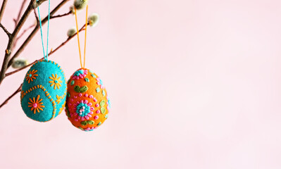 Colorful Felt Easter Eggs Hanging on Branch Against Pastel Background