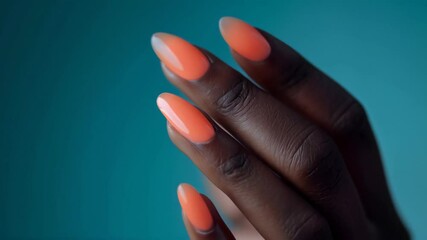 Wall Mural - Close-up of glossy orange nails on smooth fingers with a teal background, showcasing elegant polish