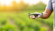 © Jiraphat - A person holds a drone over a lush green field, showcasing technology's role in modern agriculture and aerial monitoring.