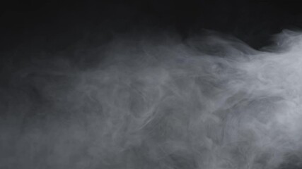 Wall Mural - thick white smoke slowly swirls and billows across a dark background, creating an eerie and atmosphe