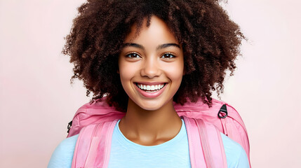 Portrait of a smiling student with curly hair and a pink backpack against a pastel pink backdrop.