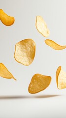 Poster - Several golden potato chips are levitating against a minimalist white backdrop, creating a visually appealing scene that emphasizes the texture and form of the popular snack