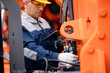 © Parilov - Machinery tractor mechanic with tablet computer checks hydraulic piston hose system equipment on excavator. Concept industry truck maintenance