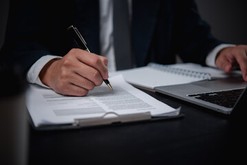 man writing on official paperwork, reflecting tasks like accounting, tax filing, or banking transactions in a corporate environment.