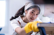© Apichat - A woman is cleaning a table with a yellow apron on
