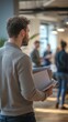 © kaiserseeing - Young man holding documents in modern office setting