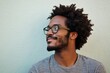 © The 2R Artificiality - Confident African American man with curly afro hairstyle wearing casual gray shirt and eyeglasses smiling thoughtfully against light green wall background