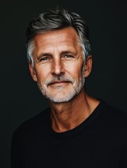Poster - mature man in black shirt with short gray hair against dark background ideal for text overlay and pr