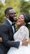 © UraiwanT - A joyful couple in wedding attire embraces outdoors, sharing a moment of laughter and love amidst a natural backdrop.