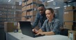 © Framestock - Warehouse or sorting center: Female logistics specialist checks E-commerce online orders on laptop. African American warehouse associate uses tablet computer, consults with colleague. Delivery service