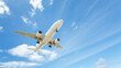 © RooM The Agency - Low angle view of an aeroplane flying in a partly cloudy blue sky