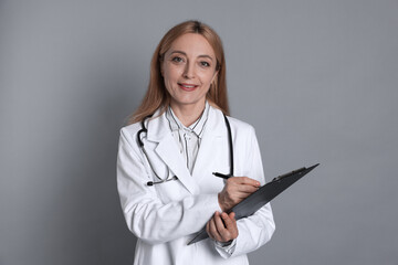 Wall Mural - Doctor with clipboard writing notes on gray background