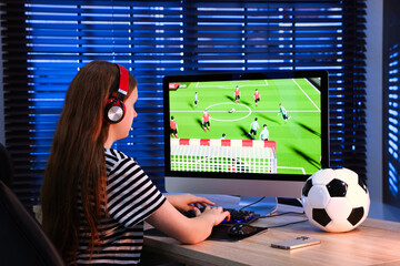 Wall Mural - Girl playing video game with keyboard at table indoors