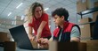 © Framestock - Two warehouse workers or logistics specialists scan parcel with scanner, prepare order for shipping to client, check information on laptop computer, work in post office. Online store delivery service.