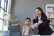 © amnaj - Two euphoric asian businesswomen celebrating a great achievement looking at a tablet in the office