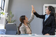 © amnaj - Two happy businesswomen celebrating successful closing deal, giving high five in modern office