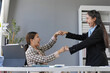 © amnaj - Two happy businesswomen are bumping fists to celebrate a successful project, demonstrating teamwork and achievement in the workplace
