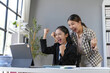 © amnaj - Two asian businesswomen are cheering with raised fists while looking at a tablet in the office, celebrating a successful project or achievement