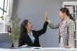 © amnaj - Two excited businesswomen are giving high five to celebrate a successful project in the office