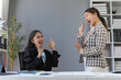 © amnaj - Two asian businesswomen celebrating success, making ok sign with fingers and smiling in the office
