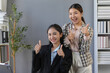 © amnaj - Two asian businesswomen showing thumbs up, expressing their agreement and satisfaction with company's success