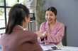 © amnaj - Two asian businesswomen sitting at desk analyzing financial charts, discussing and explaining project strategy