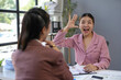 © amnaj - Asian businesswoman gesturing and explaining marketing strategy to her colleague during a meeting in office