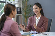 © amnaj - Two asian businesswomen are discussing a project together in a modern office, analyzing financial charts and reports