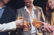 © Kritdanai - Cheers to Success: A toast to camaraderie and celebration, with four diverse individuals raising glasses of beer in a warm, dimly lit setting. Their smiles and raised glasses radiate a sense of joy.