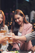 © Kritdanai - Cheers to Friendship: A group of friends raise their glasses in a toast, their smiles reflecting the warmth and camaraderie of their bond. The dim lighting creates a cozy and intimate atmosphere.