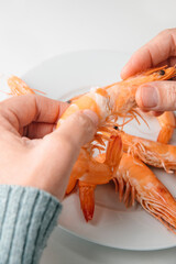 Wall Mural - man removes the head of a cooked prawn