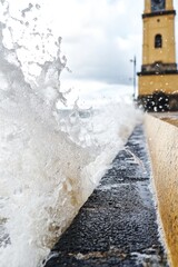 Poster - Powerful ocean wave hits a bright yellow structure