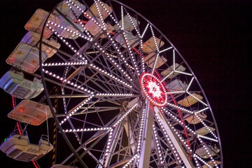 Ferris wheel rotating at night with bright lights in amusement park