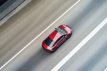 Poster - A red car drives down a road, with no other vehicles or people in sight